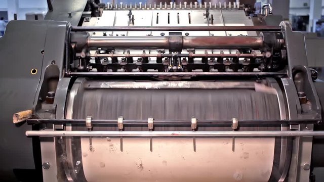 Printing Press Machine is an interesting stock video showing a press machine in a paper production site. The machine is a beautiful antique, with its faded gold and brass exterior.