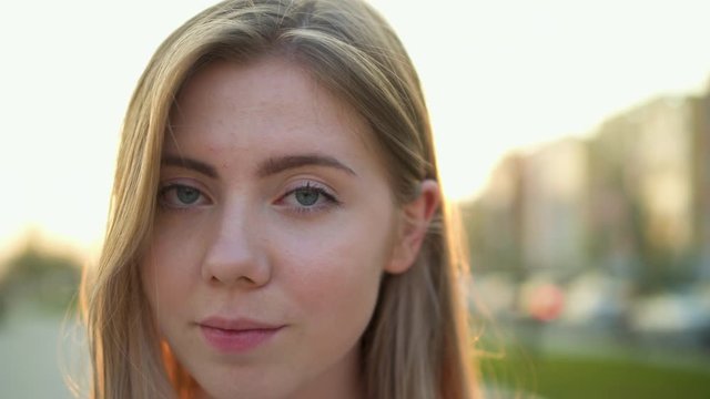 Portrait of young woman face with green eyes. Teenager with lovely look and natural make up slow motion at sunset