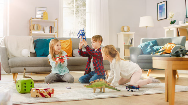 In the Living Room: Boy and Girl Playing with Toy Airplanes and Dinosaurs while Sitting on a Carpet. Sunny Living Room with Children Having Fun.