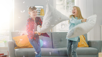 Adorable Little Boy and Sweet Little Girl Have a Pillow Fight in the Sunny Living Room. Siblings...