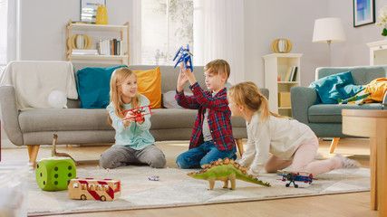 In the Living Room: Boy and Girl Playing with Toy Airplanes and Dinosaurs while Sitting on a...