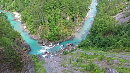 Flight of a quadcopter over a mountain's river canyon. We see the clear, transparent water of the river, it has the emerald color, the trees growing along the coast, and the mountains of northern Mont