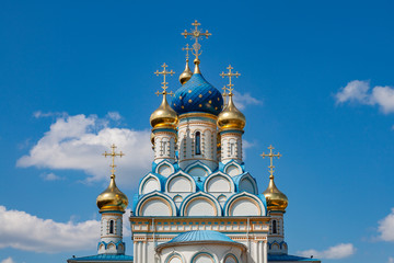 Fototapeta na wymiar Fragment of an Orthodox church with blue and gold domes against a cloudy sky
