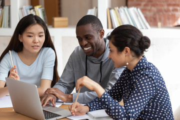 Smiling diverse students talk working on laptop together - Powered by Adobe