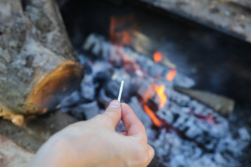 Man is holding matches in hands. Person is making fire outdoors.