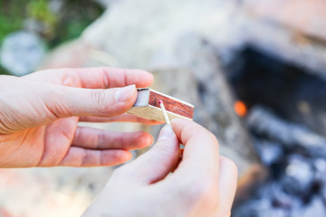 Man is holding matches in hands. Person is making fire outdoors.