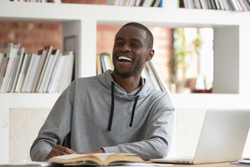 Smiling black male distracted from studying talking with someone