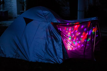 Tent with children inside glow in the night. Kids making overnight sleeping party in domestic garden. Adventure in summer vacations