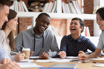 Smiling multiracial young people have fun studying together