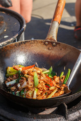 Street food. Fry the meat in a wok with vegetables - onions, bell peppers, tomatoes, seasonings and spices. Stir fry. Stirfry. Delicious gourmet food. Selective focus