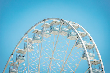 White ferris wheel cabin with blue sky in sunny day. Romantic amusement park toy
