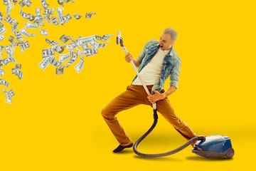 Young man having fun cleaning house with vacuum cleaner man collects money Vacuum - obrazy, fototapety, plakaty