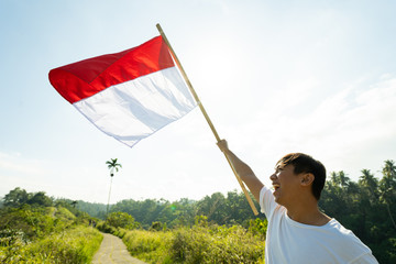 portrait of man on top of the hill in the morning rising indonesian flag celebrating independence day