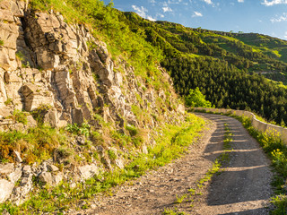 Fototapeta na wymiar Dirt road in the mountain in Georgia going uphill on a sunny evening.