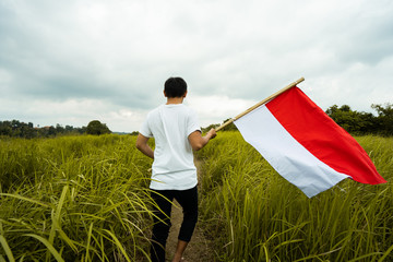 asian man with indonesian flag of indonesia on top of the mountain