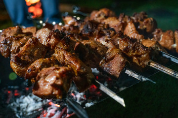 Close-up of grilled kebab on skewers on the grill at night. Well-done kebab close-up