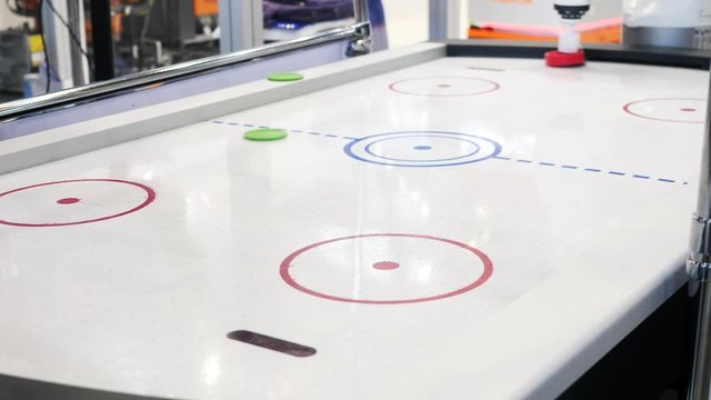 Close-up of air hockey table and person's hand playing with robot. Media. Different working robots collection presented on the robotics forum exhibition