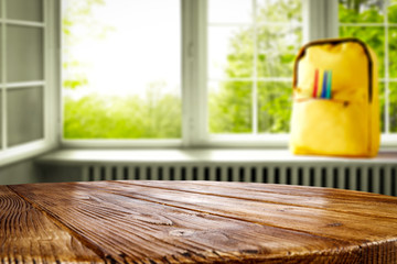 Window and wooden table top background with a yellow schoolbag on a windowsill. Empty space for products and decoration.