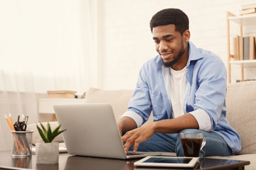 Millennial black man working on laptop in home office