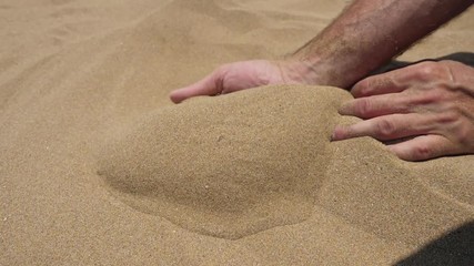 Close up view of sand running through a mans hands.