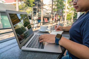 Young Asian freelancer working on laptop outdoor