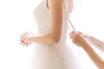 hands help the bride to zip up and put on the wedding dress 