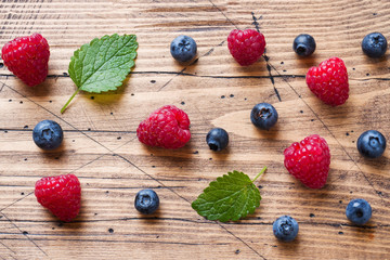 Fresh raspberries and blueberries in a wooden background.