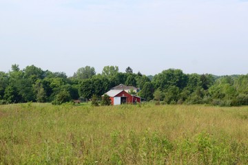 A red abandoned barn in the countryside on a sunny day.