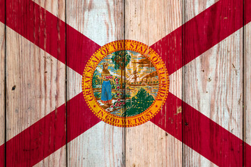 Florida US state national flag on a gray wooden boards background on the day of independence in different colors of blue red and yellow. Political and religious disputes, customs and delivery.