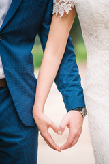 hands of bride and groom together form a heart vertical close up