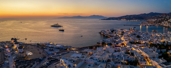 Panorama der Stadt von Mykonos bei Sonnenuntergang mit den beleuchteten Straßen und Häusern,...