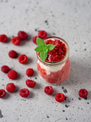 Raspberry parfait dessert Breakfast in glass jar on grey table