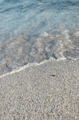 Closeup of sandy beach with soft incoming waves. Selective focus