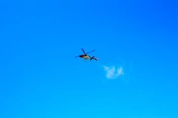 Naklejka na ściany i meble Purple helicopter tour flies against background of clear blue sky. Photo of a flying vehicle with blurred rotating blades