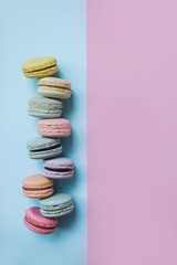 Macaron or macaroon biscuits on pastel pink and blue double background. Almond cookies of pastel colors. Top view. Copy space.