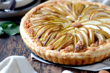 Pears tart with frangipani on a dark wooden table