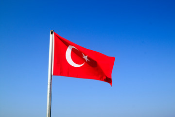 Turkish flag waving on the flagpole in the wind against the blue sky