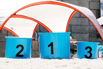 podium for winners competitors in beach with gold, silver and bronze places  in final classification