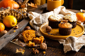 homemade tasty sweet orange pumpkin muffins or cupcakes with white cream, lavender, zest, nuts