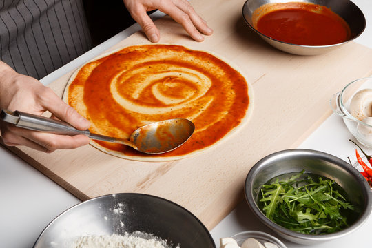 Chef Spreading Tomato Paste On Pizza Base