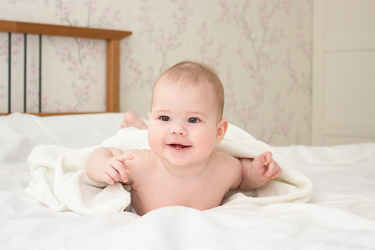 Baby girl boy 5 months under a towel. Smiling cheerful happy child european caucasian, soft focus