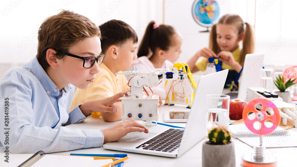 Poster Schoolboy programming diy robot with laptop at stem lesson