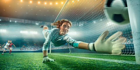Female Soccer Goalkeeper catch the ball on a professional soccer stadium. Girls playing soccer