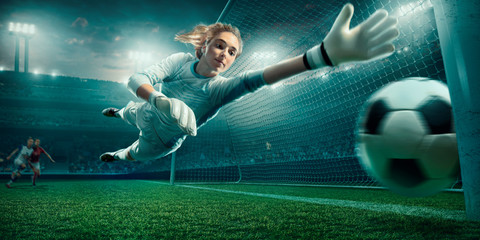 Female Soccer Goalkeeper catch the ball on a professional soccer stadium. Girls playing soccer - obrazy, fototapety, plakaty