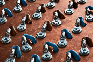 Close up macro view of copper busbar panel for high current power distribution. Cable lugs and wires connected to it with nuts and bolts.