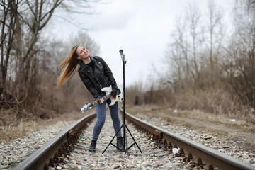  A rock musician girl in a leather jacket with a guitar