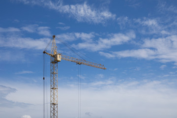 Industrial construction building crane against blue cloudy sky