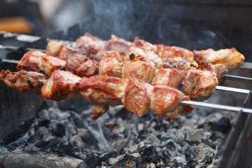 Close up selective focus fresh hot delicious bbq kebab grilling on open grill, food festival, outdoor kitchen, roasting on skewers, summer picnic, food-court