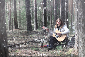 Naklejka na ściany i meble Guitarist in the woods at a picnic. A musician with an acoustic guitar in a tent in the forest. Resting with a guitar outdoors