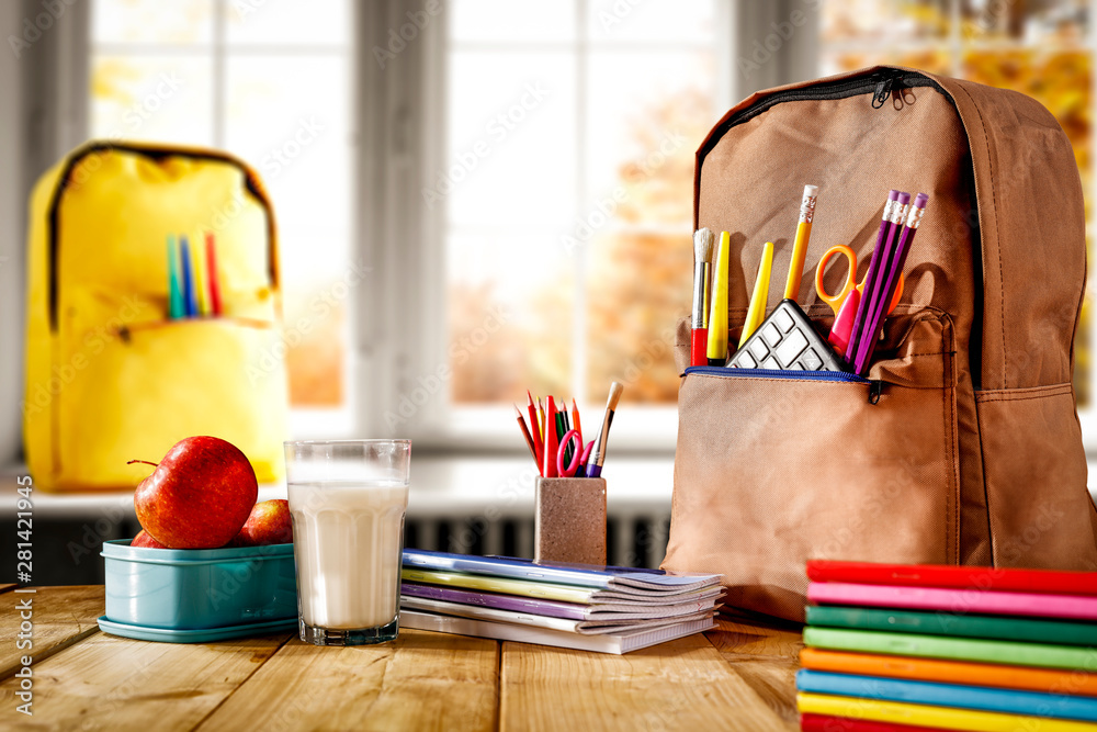 Wall mural schoolbags background with some school supplies on wooden desk top and a windowsill with white windo